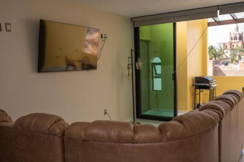 a brown couch in a living room with a large window at Casa departamento 4 hab rooftop in Arandas
