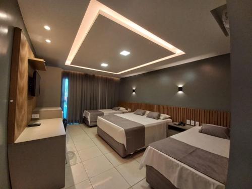 a hotel room with two beds and a television at Hotel Adventure São Luís in São Luís