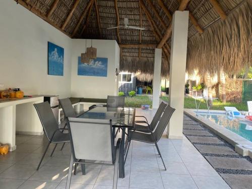 a dining room with a table and chairs and a pool at Ocean fronthouse in Salinitas in Acajutla