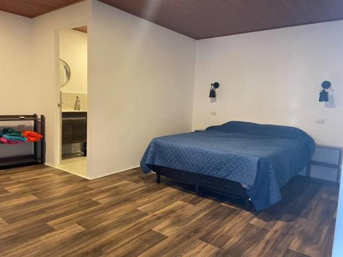 Schlafzimmer mit blauem Bett und Holzboden in der Unterkunft Ocean fronthouse in Salinitas in Acajutla