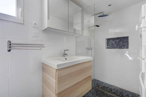uma casa de banho branca com um lavatório e um chuveiro em La Loge des Volcans - Vue Puy De Dôme em Saint-Genès-Champanelle