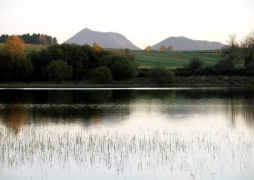 a lake with trees and mountains in the background at La Loge des Volcans - Vue Puy De Dôme in Saint-Genès-Champanelle