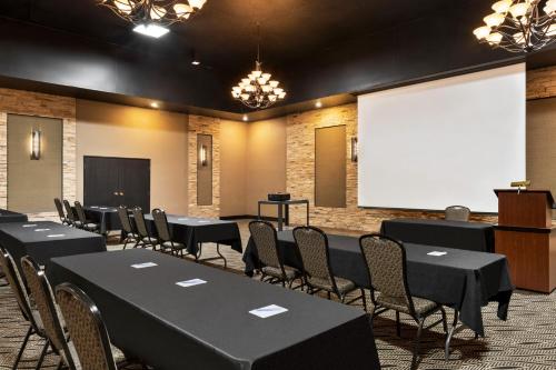 a conference room with black tables and chairs and a screen at Carrollton Hotel in Carroll