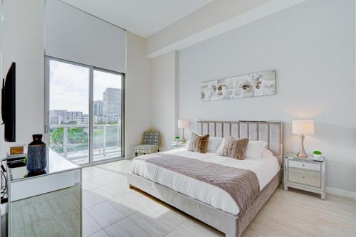 a white bedroom with a bed and a large window at 3900-504MQ DESIGN DISTRICT, CONDO 1 BEDROOM & 1 BATHROOM in Miami