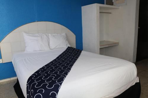 a bedroom with a white bed with a blue wall at Hotel Tropical in Progreso