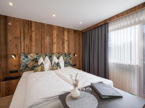 a bedroom with a white bed with a wooden wall at Riemenerhof in Fügen
