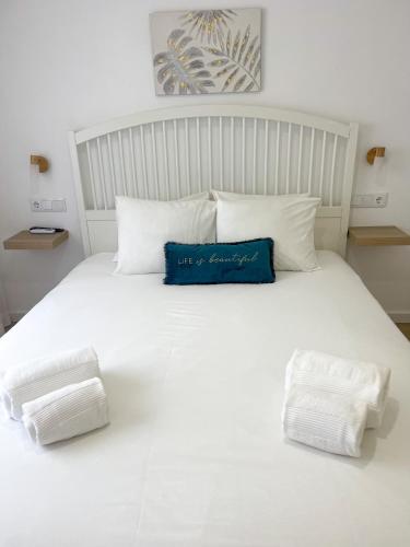a large white bed with a blue pillow on it at Solbelo Quarteira Beach in Quarteira