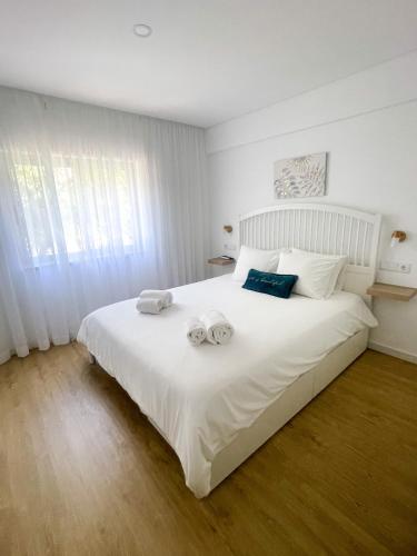 a bedroom with a large white bed with towels on it at Solbelo Quarteira Beach in Quarteira
