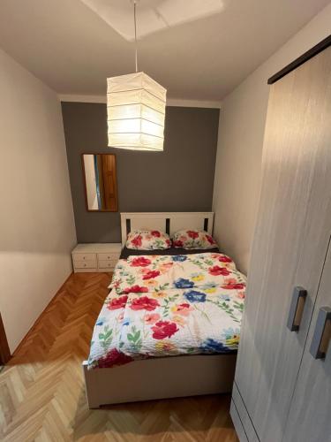 a bedroom with a bed with a floral comforter at Stan na dan Apartman TRG in Derventa