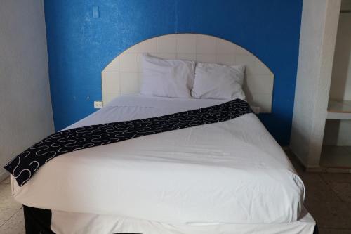 a bed with a black and white blanket on it at Hotel Tropical in Progreso