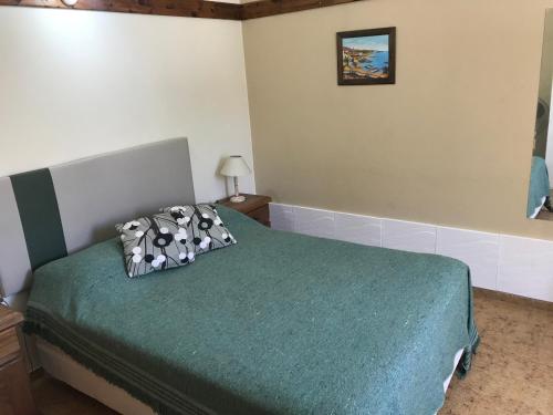 a bedroom with a bed with a green blanket at Complejo El Pinar in Las Grutas