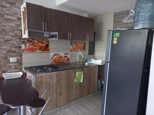 a kitchen with a refrigerator and a sink and a stove at Apartamento en Ricaurte, Arrayanes de Peñaliza in Ricaurte