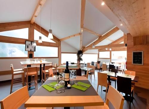 ein Esszimmer mit Tischen, Stühlen und Fenstern in der Unterkunft CozyLoge, Orelle & Les 3 vallées in Orelle