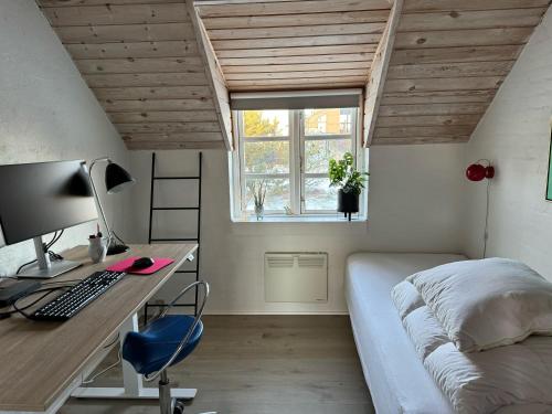 a bedroom with a bed and a desk with a computer at Viking Surf Cottage in Klitmøller
