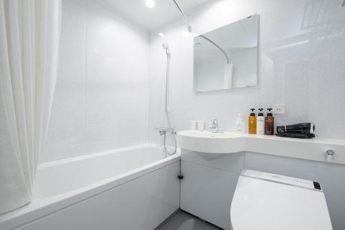 La salle de bains blanche est pourvue d'une baignoire, de toilettes et d'un lavabo. dans l'établissement The One Five Garden Kurashiki - Vacation STAY 40175v, à Kurashiki