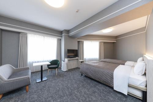 Cette chambre comprend un lit, une chaise et un bureau. dans l'établissement The One Five Garden Kurashiki - Vacation STAY 40175v, à Kurashiki