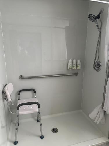 a shower with a chair in a white bathroom at Wingate by Wyndham North Little Rock in North Little Rock