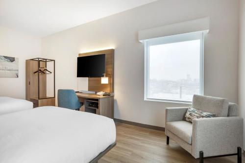 a hotel room with a bed and a desk and a window at Comfort Inn & Suites Newark Liberty International Airport in Newark