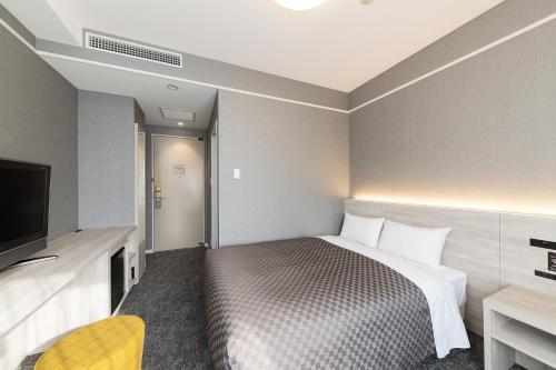 a hotel room with a bed and a flat screen tv at The One Five Garden Kurashiki - Vacation STAY 40159v in Kurashiki