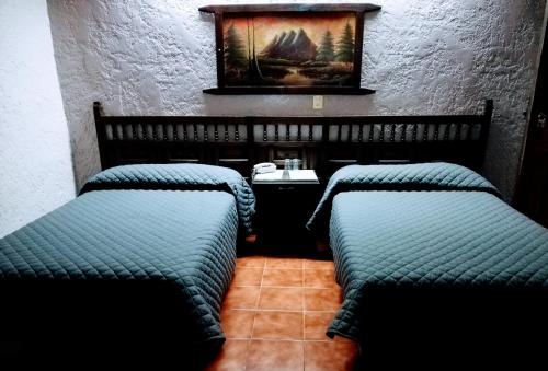 three beds in a room with a painting on the wall at Hotel Iberia in Córdoba