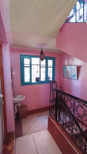 a bathroom with pink walls and a staircase with a sink at Hôtel Restaurant BOUGAFER in Oulad Akkou