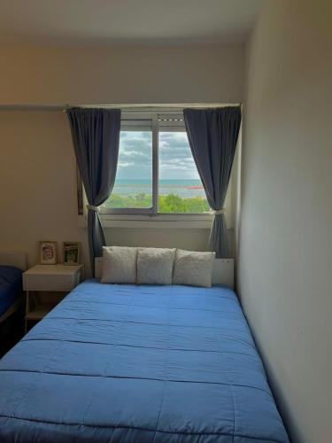 Un dormitorio con una cama azul y una ventana en departamento playa grande en Mar del Plata