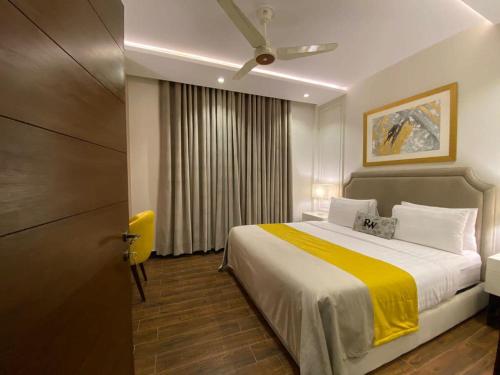 a bedroom with a bed with a yellow blanket at Rosewood Lahore in Lahore
