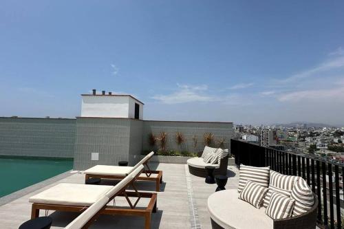 a balcony with chairs and tables on a roof at Apartamento en Barranco in Lima