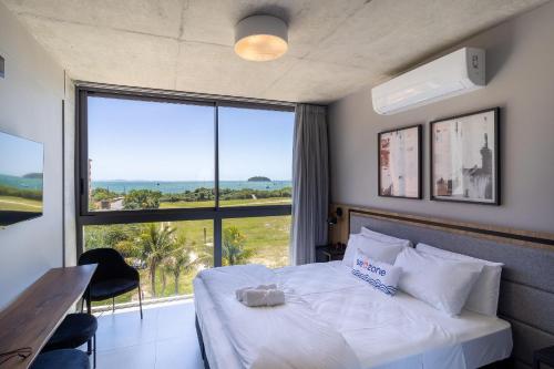 um quarto de hotel com uma cama e uma grande janela em Spot Jurere sofisticação à beira mar - SPJ's em Florianópolis