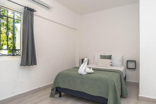 a white bedroom with a bed and a window at La Quinta Caribeña in Playa del Carmen