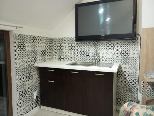 a bathroom with a sink and a tv on a wall at Apartament with nice city view in Dezmir