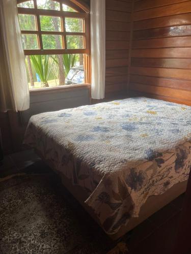 een bed in een kamer met een raam bij Chalé aconchegante in Itu