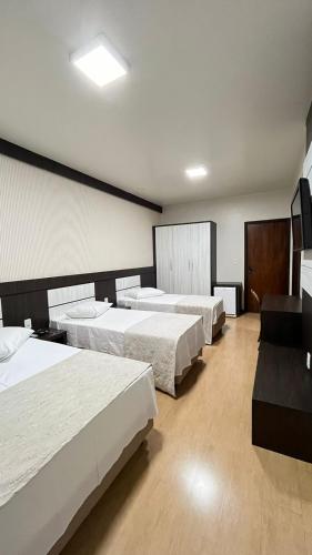 a hotel room with three beds and a television at Regente Hotel in Pato Branco