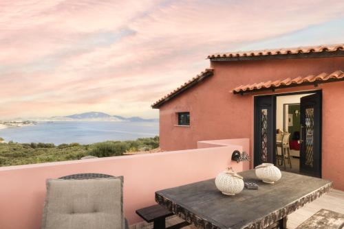 a house with a balcony with a table and chairs at Athenea Villas, Private Pools & Gardens in Keri