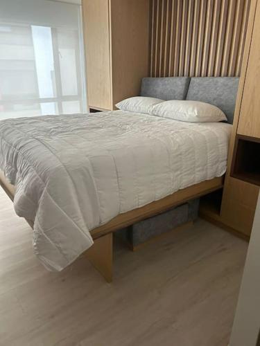 um quarto com uma cama com um cobertor branco em Apartamento en Usaquen em Bogotá