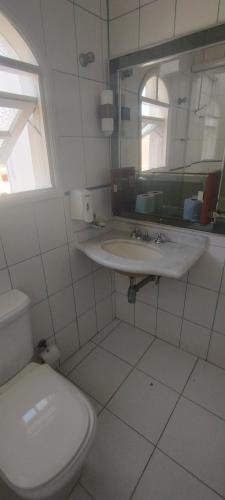 a white bathroom with a toilet and a sink at Hotel Casa Branca in Guarujá
