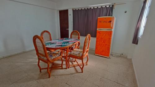 a dining room table and two chairs and a refrigerator at Hotel Tropical in Progreso