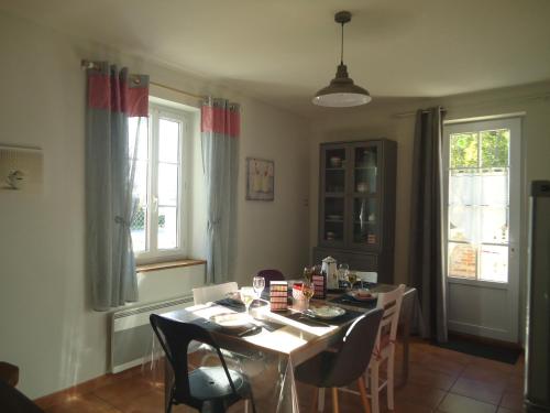 a dining room with a table and chairs and windows at Bienvenue à la halte de Sigournais ancienne Gare in Sigournais