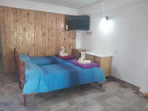 Un dormitorio con una cama azul con cisnes. en Jireh en Esquel