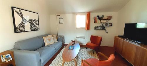 uma sala de estar com um sofá azul e uma televisão em La Cachette village em Roussillon