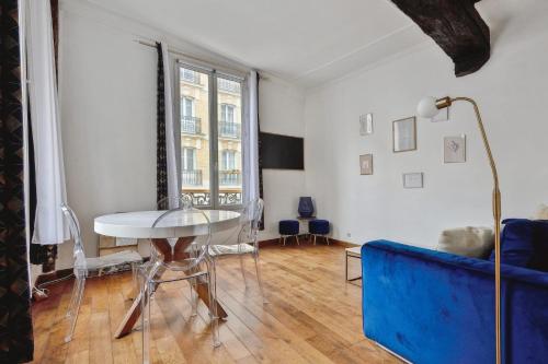 ein Wohnzimmer mit einem Tisch und einem blauen Sofa in der Unterkunft Charming T2 in 2nd arrond of Paris - Welkeys in Paris