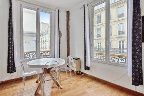 une chambre avec une table et deux grandes fenêtres dans l'établissement Appartement Montare - Welkeys, à Paris