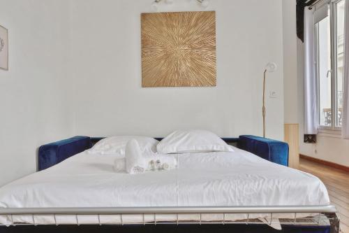 ein Bett mit weißer Bettwäsche und Kissen darauf in der Unterkunft Charming T2 in 2nd arrond of Paris - Welkeys in Paris