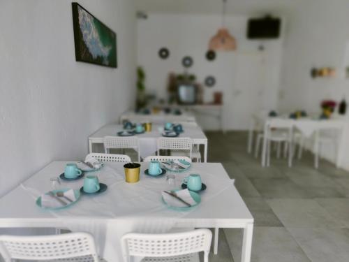 a dining room with white tables and white chairs at Villa Paraíso da Caparica in Charneca
