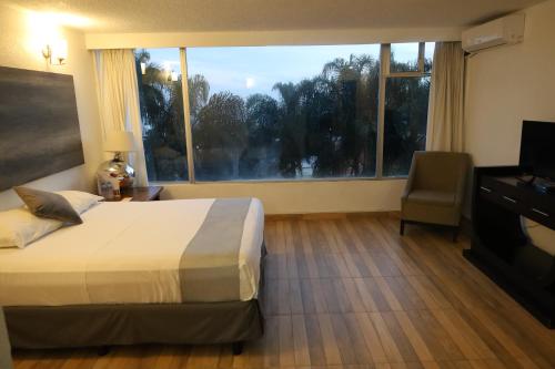a hotel room with a bed and a large window at Hotel Grand Vista Cuernavaca in Cuernavaca