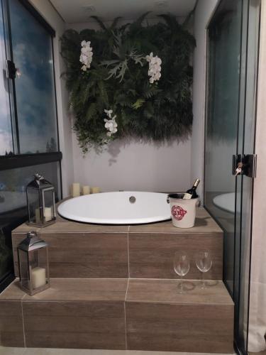 a bath tub in a bathroom with two wine glasses at Wanderlust Experience Hotel Best Western in Campos do Jordão