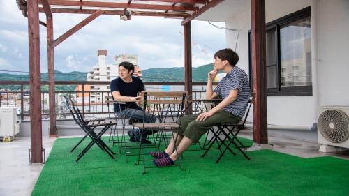 2 uomini seduti su un balcone con sedie di Guesthouse Danran - Vacation STAY 36999v a Beppu