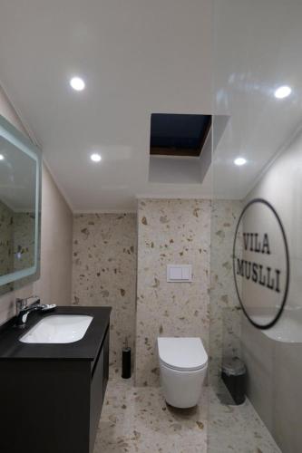 a bathroom with a toilet and a sink and a mirror at Vila Muslli in Korçë