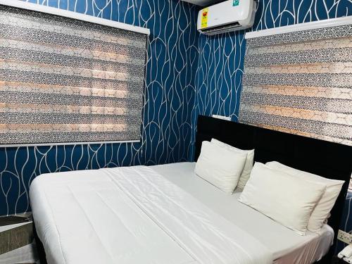 a bedroom with a white bed with a blue wall at Covenant Hotel in Accra