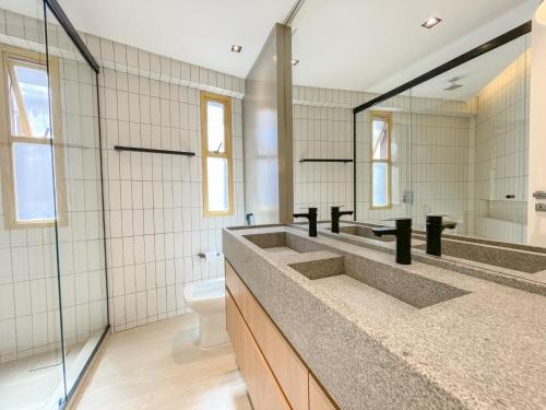 een badkamer met 2 wastafels, een toilet en een spiegel bij Luxuoso apartamento com a melhor vista de BC in Balneário Camboriú